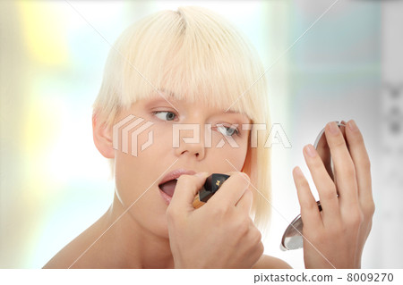 A beautiful young woman applying her make-up A beautiful young woman applying her make-up 8009270