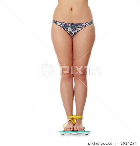 Female legs on scale tied up with measuring tape 8014254