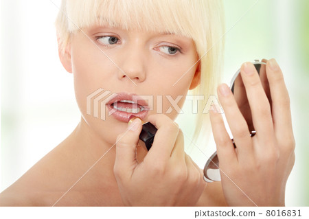 A beautiful young woman applying her make-up 8016831