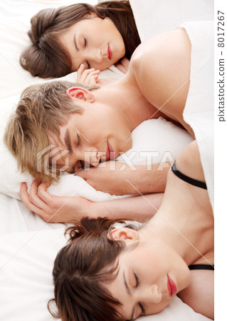 Handsome man lying in bed with two girls Handsome man lying in bed with two girls 8017267