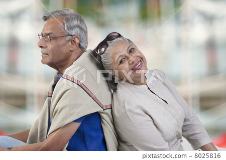Old couple sitting back to back 8025816