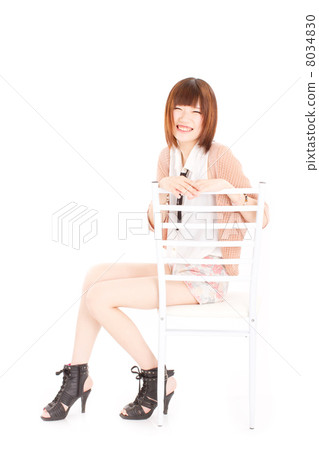 坐在一張純白色的椅子上，笑容十足的小女孩帶著美妙的笑容 8034830