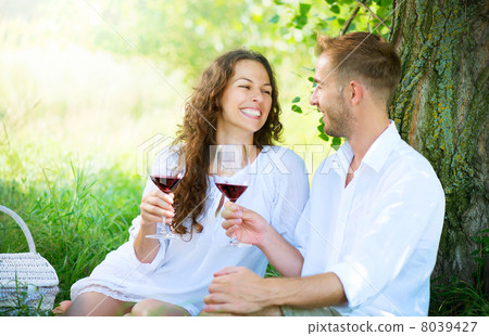 Picnic. Young Couple relaxing and drinking Wine in a Park 8039427