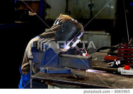 Welder working in production workshop on a workbench Welder working in production workshop on a workbench 8065965