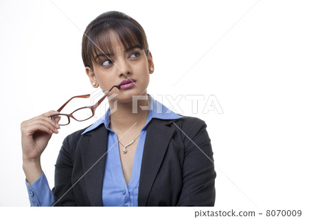 Beautiful young businesswoman holding glasses while looking away Beautiful young businesswoman holding glasses while looking away 8070009