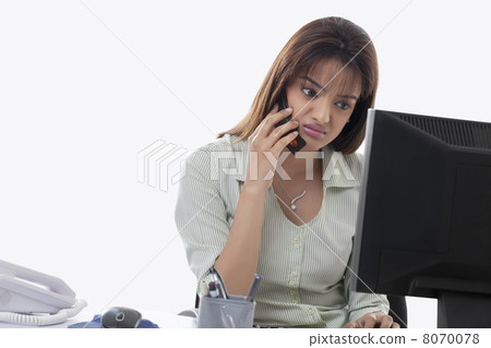 Angry female executive on call while using computer Angry female executive on call while using computer 8070078