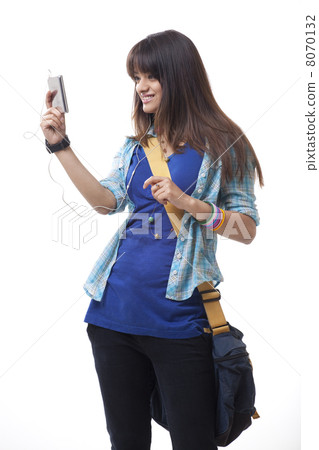 Young woman with backpack listening to music over white background 8070132