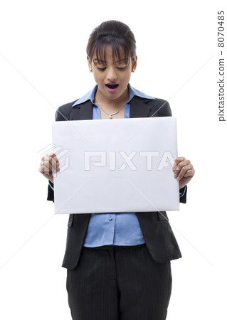 Portrait of surprised young businesswoman holding blank card over white background 8070485
