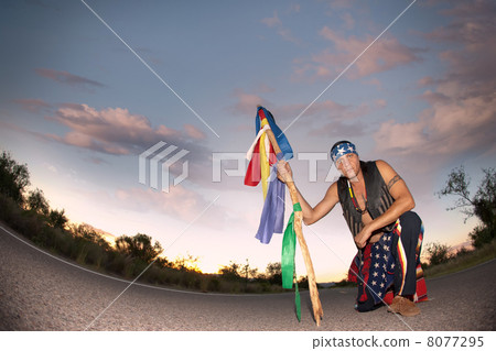 Indigenous man in the middle of a road with ceremonial pole and 8077295