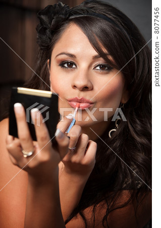 Beautiful Latina Woman with Compact Applying Lip Gloss 8077456