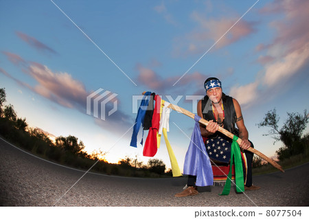 Indigenous man in the middle of a road with ceremonial pole and 8077504