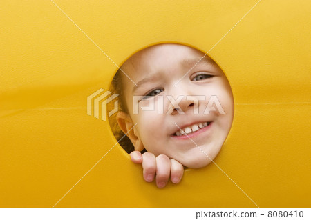 Little girls face through a hole in play equipment 8080410