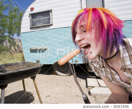 Girl in front of a trailer eating a hotdog 8081406