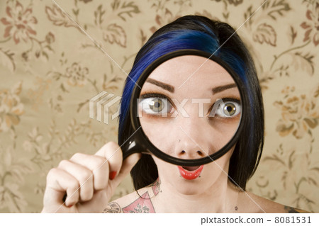 Pretty Woman with a Magnifying Glass in front of her Face 8081531