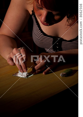 Young woman cutting cocaine or heroin Young woman cutting cocaine or heroin 8082508