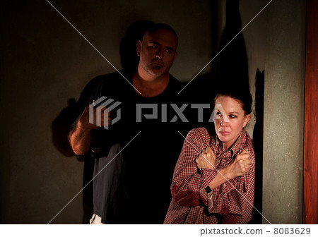 Frightened woman in hallway with menacing man Frightened woman in hallway with menacing man 8083629