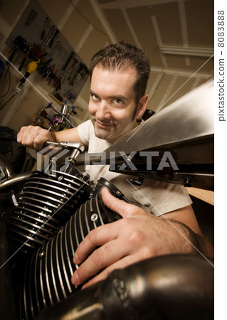 Man in garage working on motocycle 8083888