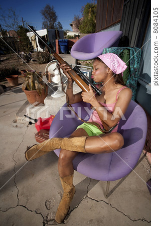 Black woman on back patio kissing rifle 8084105
