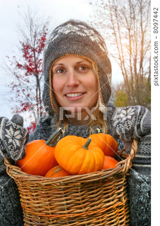 Young woman holding a basket full of pumpkins Young woman holding a basket full of pumpkins 8097442