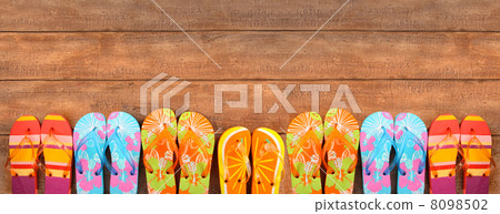 Brightly colored flip-flops on wood 8098502