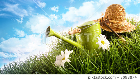 Water can and straw hat laying in grass 8098874