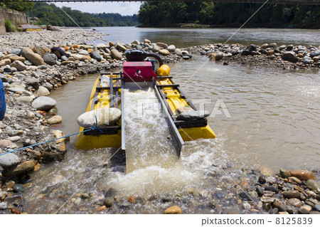 Suction dredge mining alluvial gold on an Amazonian riverbank in Ecuador 8125839