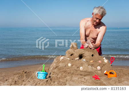 Elderly man with sand castle 8135163