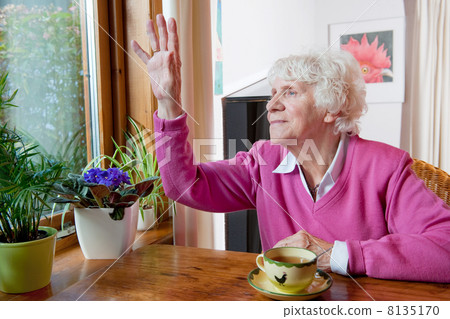 Depressed elderly woman sitting at the table 8135170
