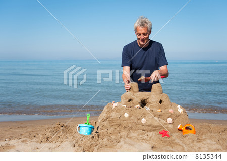 Elderly man with sand castle Elderly man with sand castle 8135344