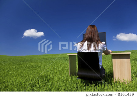 Woman Using Computer at Desk in Green Field Woman Using Computer at Desk in Green Field 8161439