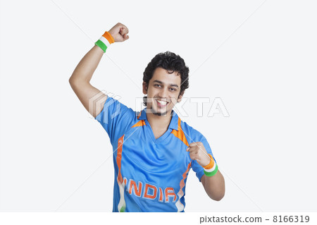 Portrait of young man in Indian cricket team jersey cheering up with clenched fists over white background 8166319