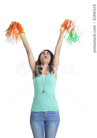 Young woman in casual wear holding up tricolor pom poms over white background Young woman in casual wear holding up tricolor pom poms over white background 8166328