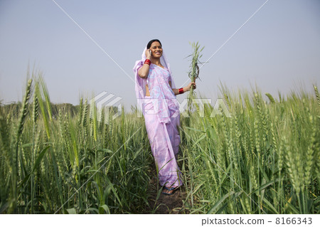 Low angle view of Indian female farm worker talking on mobile phone Low angle view of Indian female farm worker talking on mobile phone 8166343