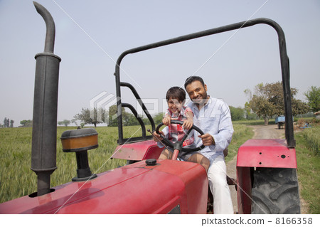 Portrait of father and son driving a tractor 8166358