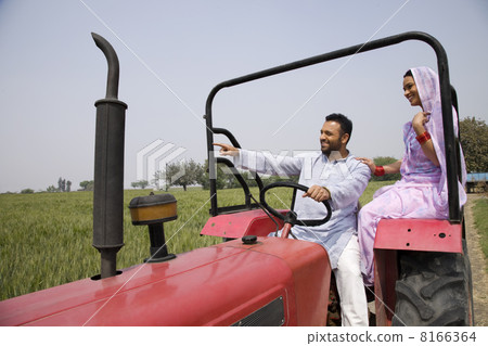 Indian couple on tractor with man pointing at something Indian couple on tractor with man pointing at something 8166364