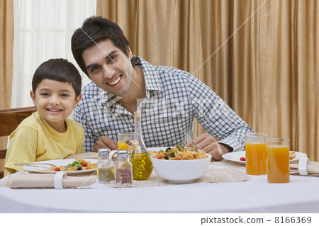 Portrait of a happy father and son having pizza at table 8166369