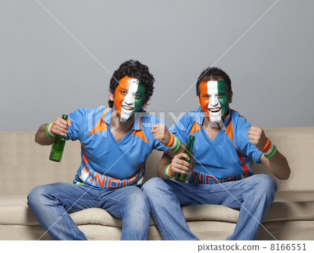 Portrait of male friends on sofa with painted face cheering while having drink at home Portrait of male friends on sofa with painted face cheering while having drink at home 8166551