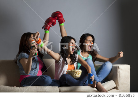 Enthusiastic young female friends screaming out while watching boxing match together at home Enthusiastic young female friends screaming out while watching boxing match together at home 8166855