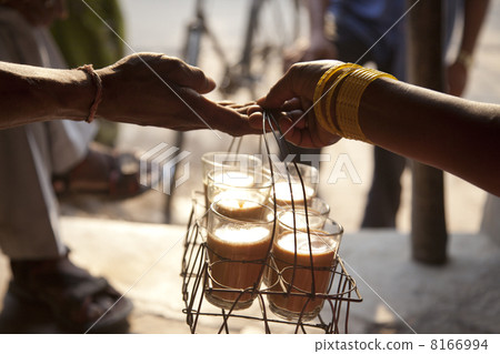 Close-up of females hand passing tray of chai to man with people in background 8166994