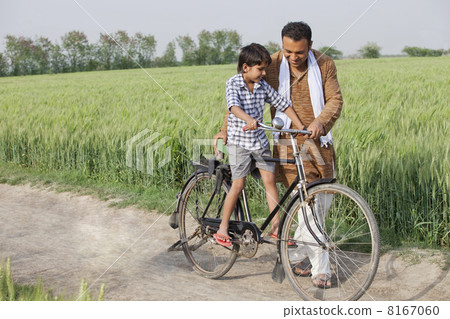 Father teaching son how to ride cycle 8167060
