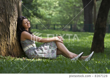 Young woman leaning against a tree 8167128