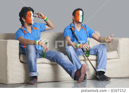 Disappointed young male friends with painted face looking away while holding bottle Disappointed young male friends with painted face looking away while holding bottle 8167152