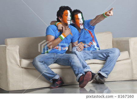 Full length of excited male friends with face painted in Indian tricolor sitting on sofa Full length of excited male friends with face painted in Indian tricolor sitting on sofa 8167160