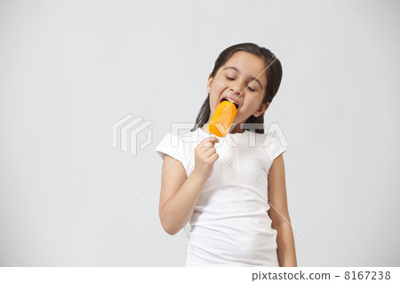 Happy little girl eating ice lolly isolated over gray background Happy little girl eating ice lolly isolated over gray background 8167238