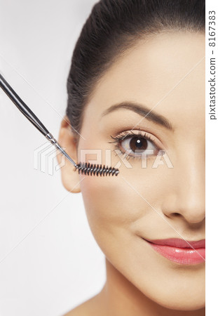 Smiling young woman applying mascara Smiling young woman applying mascara 8167383