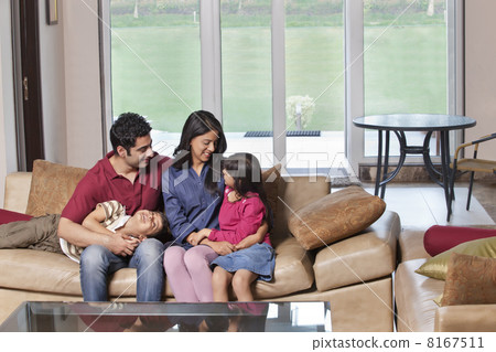 Young parents sitting with kids on sofa at home 8167511