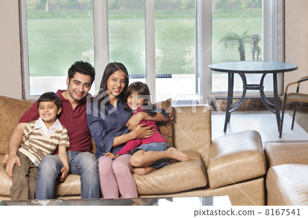 Portrait of happy Indian family of four sitting together on sofa 8167541