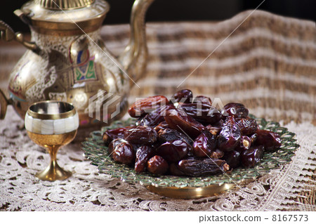 Close-up of an ornamental bowl of dried dates with kettle and glass Close-up of an ornamental bowl of dried dates with kettle and glass 8167573