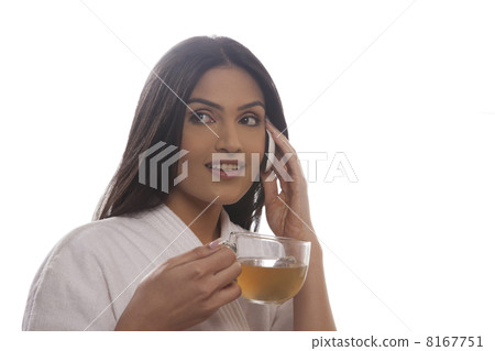 Young woman holding tea cup while using cell phone 8167751