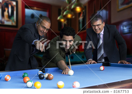 Young man playing snooker while senior businessmen standing by pool table 8167753